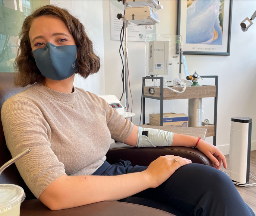 Emily sitting at an infusion clinic, wearing the PICCPerfect® Active PICC Line Cover in Mist.
