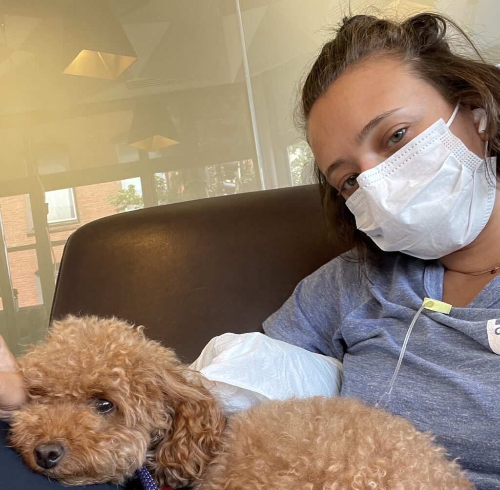Emily, with her emotional support dog, Olive, while receiving care while living with a port
